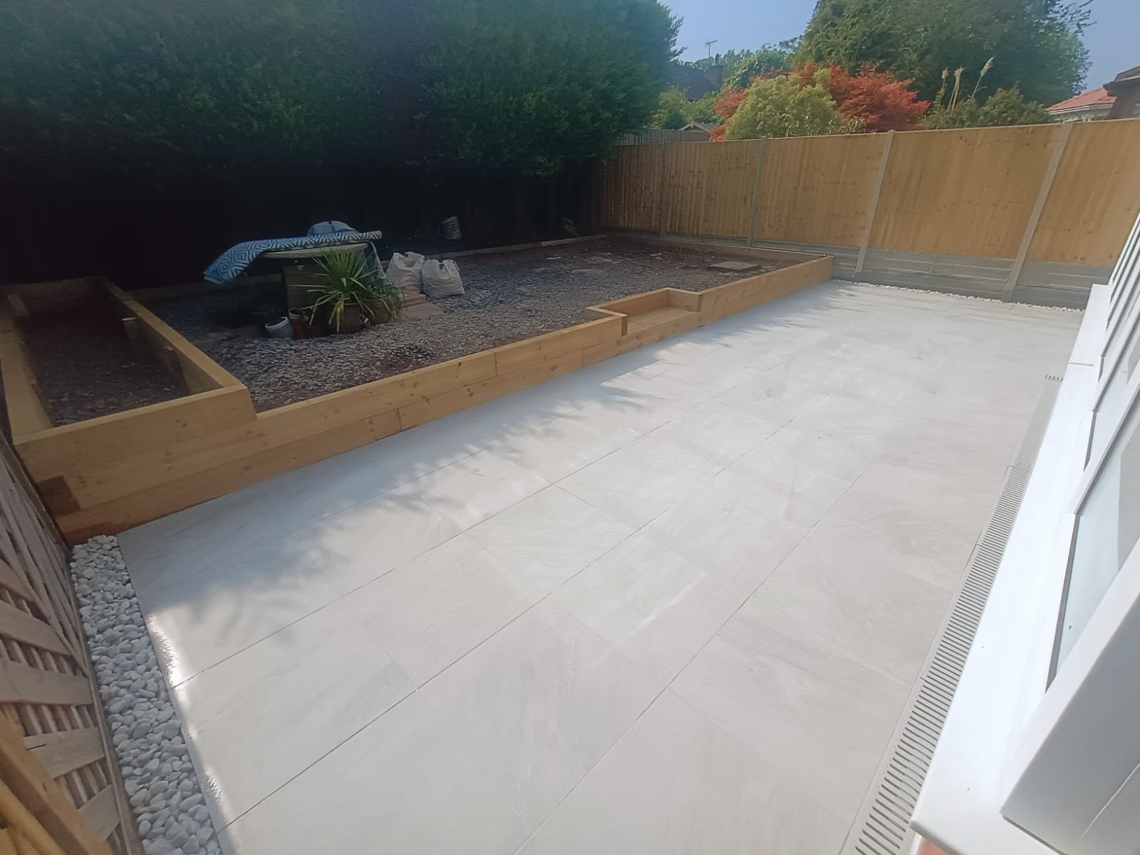 Raised flower beds with modern porcelain patio and wooden fence panels